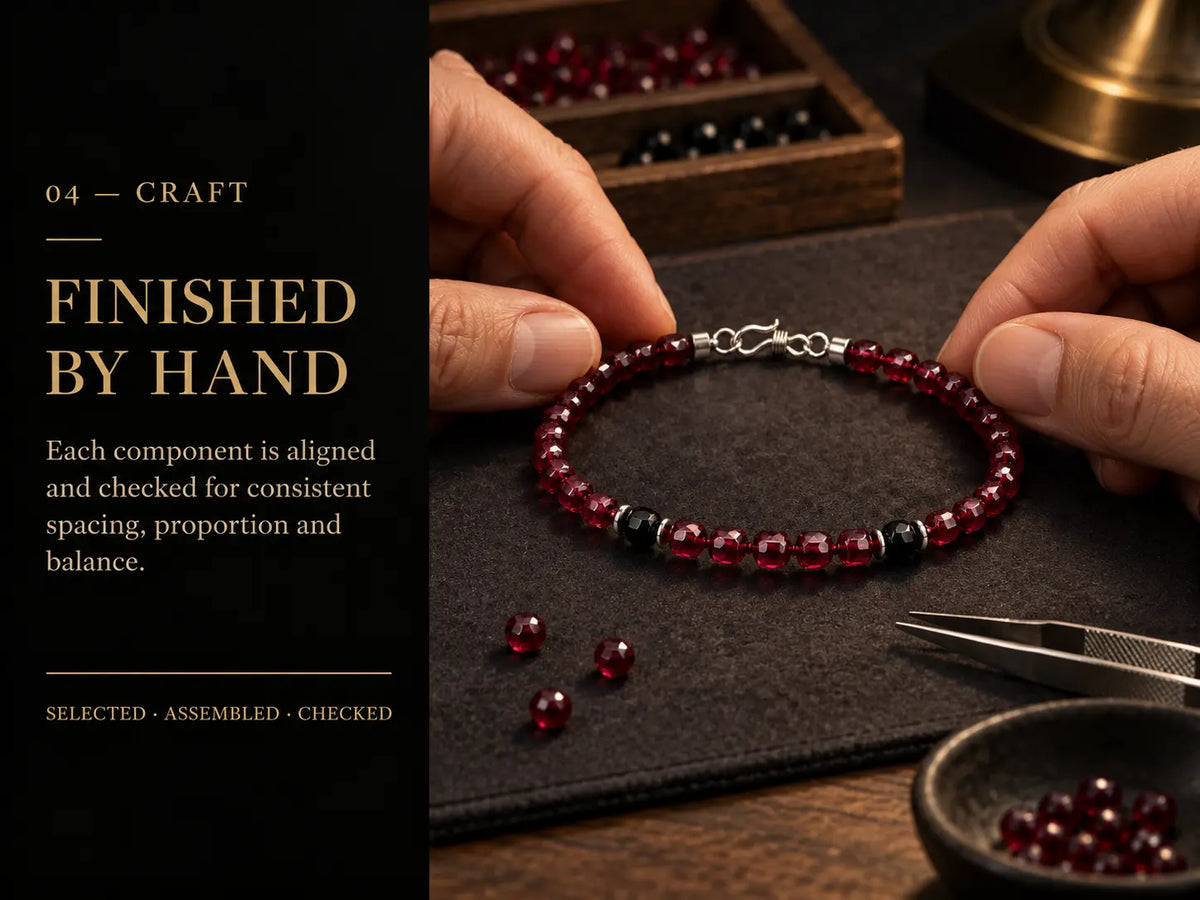 Natural garnet bracelet being aligned and inspected by hand at the workbench.